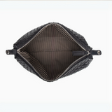 Interior view of black woven leather toiletry bag featuring spacious striped lining and secure zip closure.