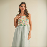 vClose-up of model showcasing floral patchwork bodice with scalloped trim and green striped skirt
