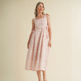 Woman wearing pink floral ruffle strap midi dress with side bows and tiered skirt

