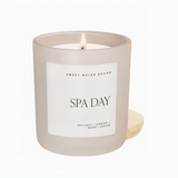 Hand holding a lit Spa Day candle on a wooden board, featuring minimalist label design

