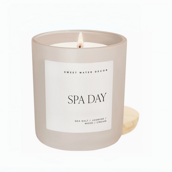 Hand holding a lit Spa Day candle on a wooden board, featuring minimalist label design

