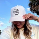 Woman wearing the trucker hat, smiling under a bright blue sky.