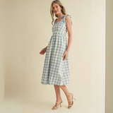 Model standing in a blue gingham dress, showing side profile and pockets

