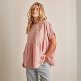 Three-quarter view showing peplum silhouette and chest pocket detail on pink top.
