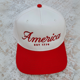 Front view of America EST. 1776 snapback hat on textured surface

