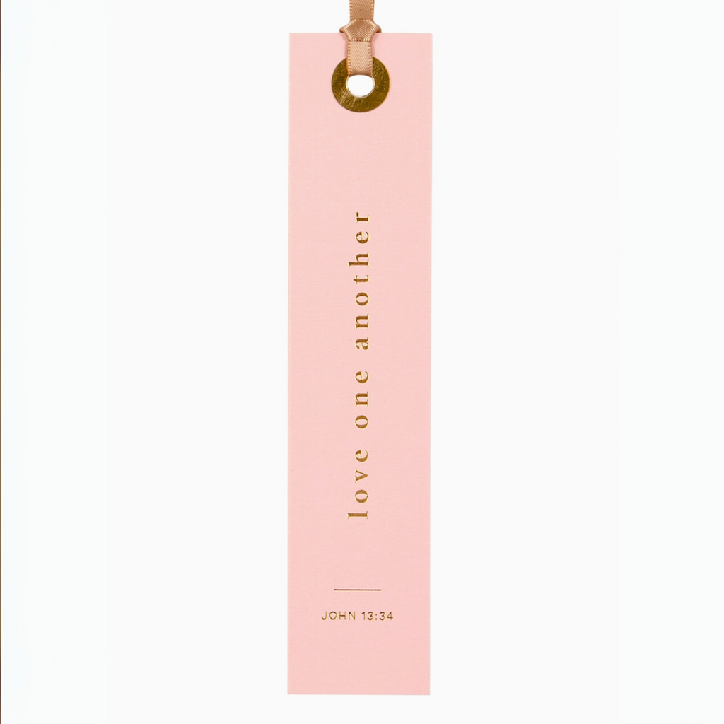 "Pink foil-pressed bookmark with scripture John 13:34 - 'Love one another' in gold lettering."

