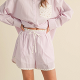 Model wearing pink striped shorts with floral accents and hands on hips.

