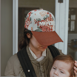 "Close-up of a floral embroidered trucker hat with the word 'MOTHER' in bold lettering, featuring an adjustable fit and earthy tones."

