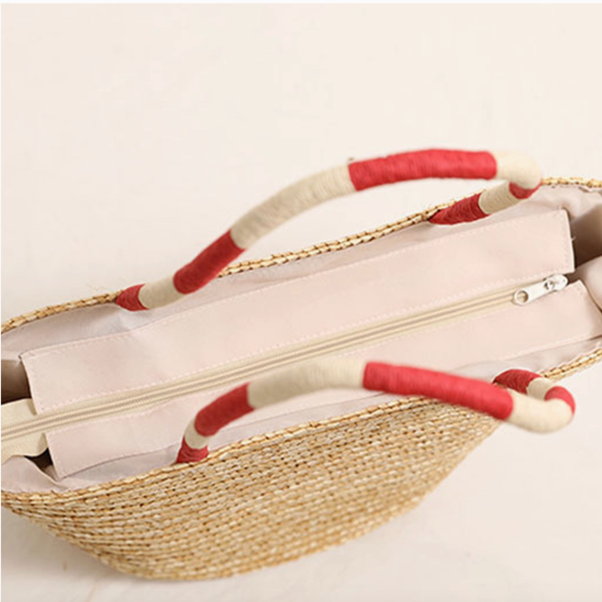 Top view of straw tote bag showing beige fabric lining and zipper closure.

