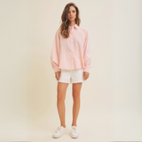 Full-body shot of the model styling the blouse with white shorts and sneakers.