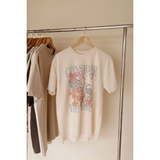 Consider the Lilies graphic tee hanging on a clothing rack with neutral-colored shirts.
