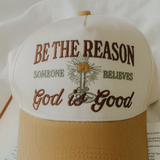 Flat-lay of two-tone embroidered Christian baseball cap with candle design.

