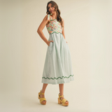 Angled side view of model posing in patchwork midi dress with floral bodice and pockets
