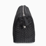 Side view of black woven leather toiletry bag highlighting durable construction and zipper detail.