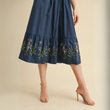 Close-up of floral embroidery detail on navy blue dress hem.