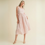 Woman wearing pink floral ruffle strap midi dress with side bows and tiered skirt

