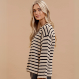 Side profile view of a striped knit pullover sweater with a drop-shoulder design and raw edge detail.