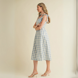 Side view of model wearing light blue checkered midi dress with tie straps


