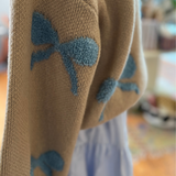 Close-up of the Ribbon Pattern Balloon Sleeve Sweater, highlighting the textured ribbon patterns on soft beige fabric.