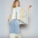 Model seated in relaxed pose wearing oversized denim and paisley print kimono top with frayed hem and mixed prints.