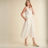 Model twirling in white tie-back V-neck midi dress with a fitted waist.