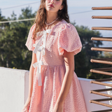 Angled view of the textured pink dress, emphasizing the flowing silhouette and elegant design.