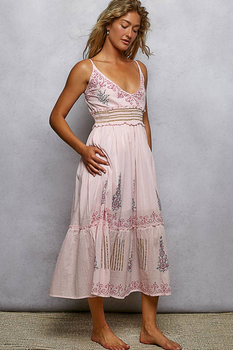 Woman wearing a pink embroidered dress against a plain background