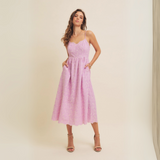 Full-length shot of woman wearing lilac midi dress with scalloped hemline.
