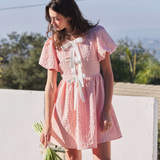 Close-up front view of the pink mini dress highlighting the short bubble sleeves and white bow tie accents.