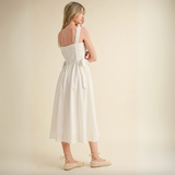 Back view of midi dress with smocked panel and bow detail at the waist.