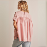 Back view of blush pink peplum top featuring back keyhole button closure and gathered detailing.