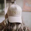 Front view of the "Yeshua" 5-panel hat showcasing navy puff embroidery on the brown cap.​


