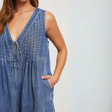 Model wearing the pleated denim romper styled with sneakers for a casual look.