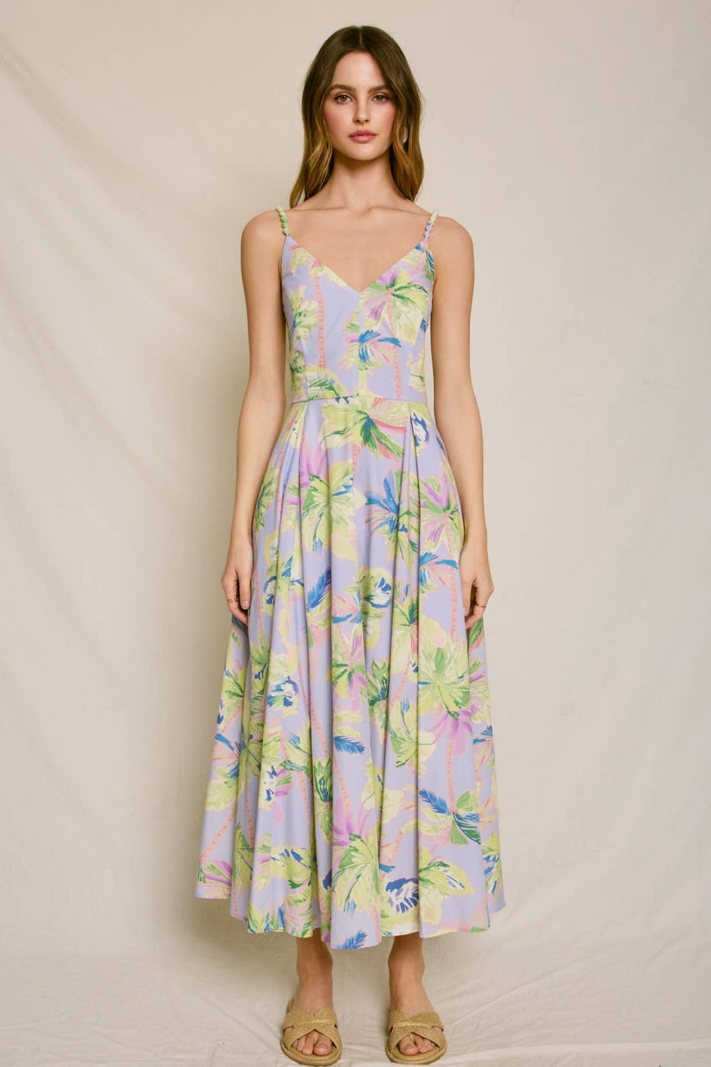 Woman wearing a pastel floral dress against a plain background