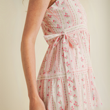 Woman wearing pink floral ruffle strap midi dress with side bows and tiered skirt

