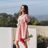 Side profile of a pink mini dress, showcasing textured fabric and elegant bow tie details.