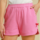 Close-up view of Bubble Pink Textured Shorts showing red bow detail on the hem.