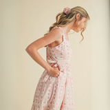 Woman wearing pink floral ruffle strap midi dress with side bows and tiered skirt

