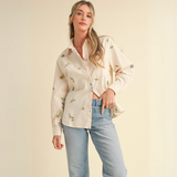 Side profile of the embroidered button-down shirt paired with light denim jeans.