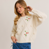 Side view of the Strawberry Embellished Knit Sweater styled casually, featuring strawberry embroidery and dimensional flower accents.