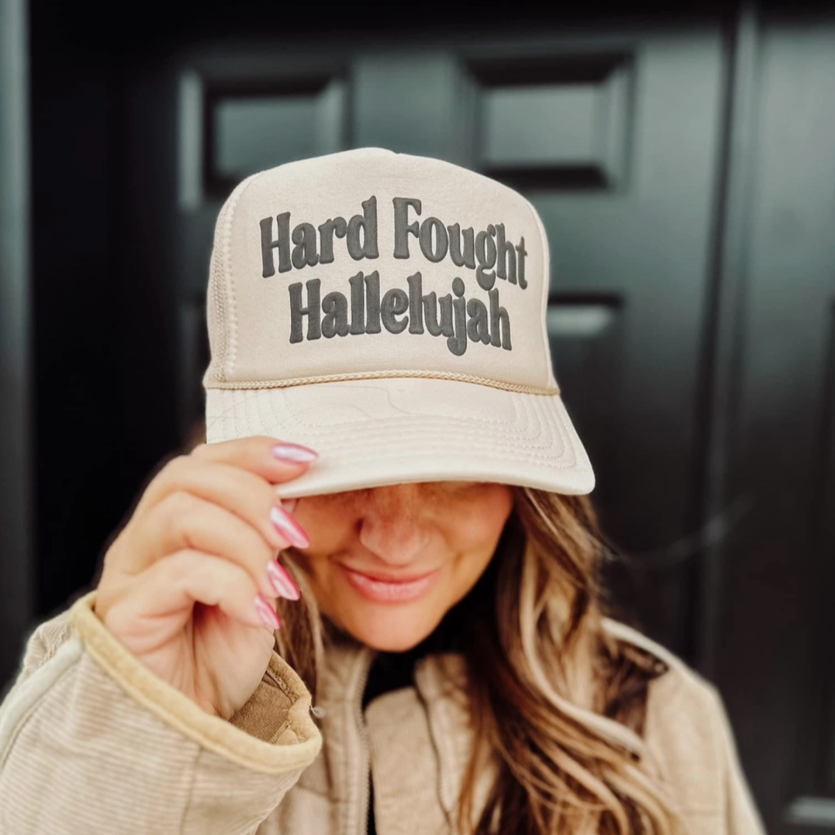 Front view of the "Hard Fought Hallelujah" Trucker Hat showcasing the black puff ink design.