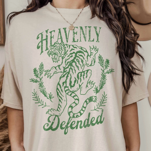 Close-up of a woman wearing the "Heavenly Defended" oversized graphic tee featuring a green tiger and laurel design.