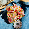 Colorful scrunchie on a denim surface with 'cast these' brand tag.