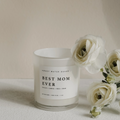 Minimalist white “Best Mom Ever” soy candle with black text, surrounded by white flowers – 11oz jar with sea salt, jasmine, wood, and cream scent.

