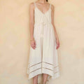 Woman wearing a white dress with thin straps against a beige background
