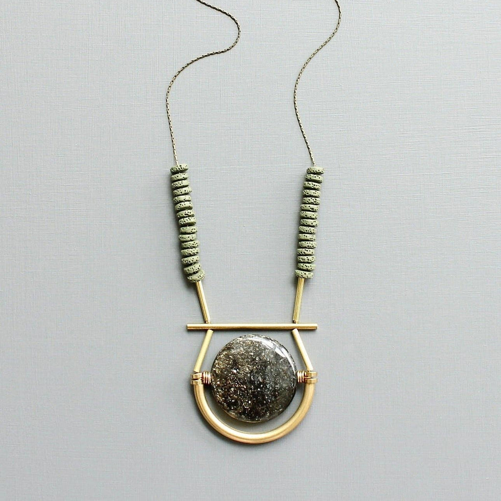 Necklace with geometric design and beads on a light gray background