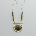 Necklace with geometric design and beads on a light gray background